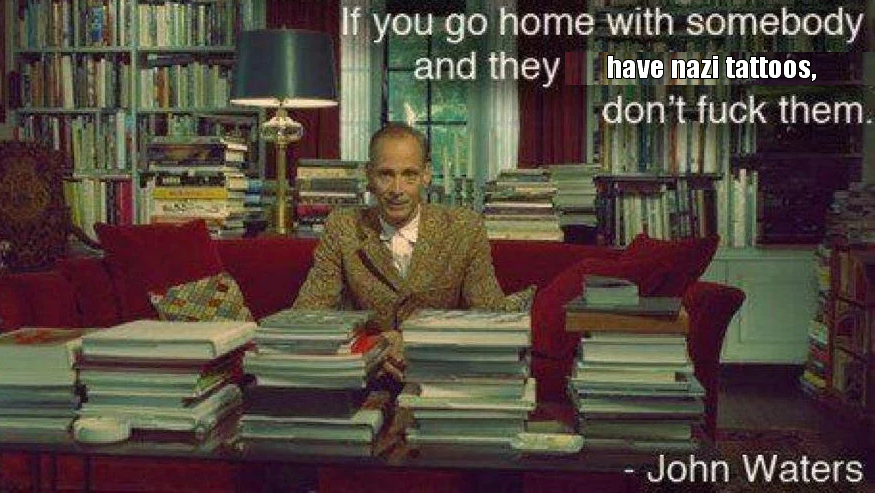 This meme is a screenshot of a photo of a man sitting at a desk surrounded by books and papers, with a faintly amused expression. The text overlay reads: "If you go home with somebody and they have a tattoo of your ex's name on their body, it's time to re-evaluate that relationship." Below this, a second text overlay reads: "On the other hand, if they have a tattoo of your name on their body, it's a sign that you're in a healthy relationship." The image is then followed by a quote from John Waters, a famous American filmmaker, which reads: "I love people who have a tattoo of my name on their body. It's like, I'm not a great lover, I'm a great friend. If you go home with somebody and they have a tattoo of your ex's name on their body, it's time to re-evaluate that relationship."